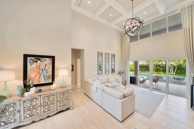 living room with coffered ceiling, beam ceiling, a chandelier, a high ceiling, and light hardwood / wood-style floors