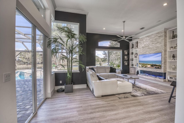 living room with crown molding, ceiling fan, built in shelves, and light hardwood / wood-style flooring