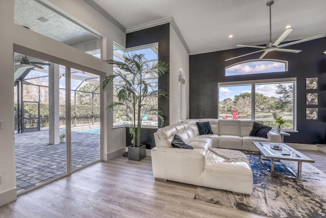 living room featuring ornamental molding, a towering ceiling, hardwood / wood-style floors, and ceiling fan