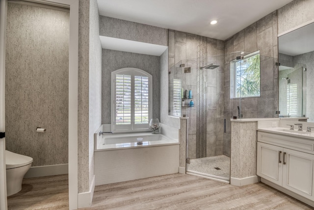 bathroom with a stall shower, wallpapered walls, vanity, and wood finished floors