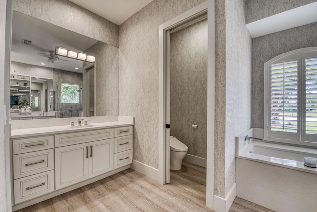 full bathroom featuring visible vents, toilet, vanity, wood finished floors, and wallpapered walls