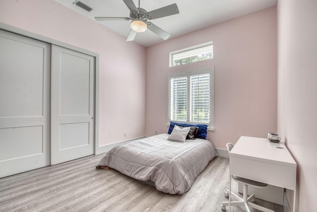 bedroom with ceiling fan, light hardwood / wood-style floors, and a closet