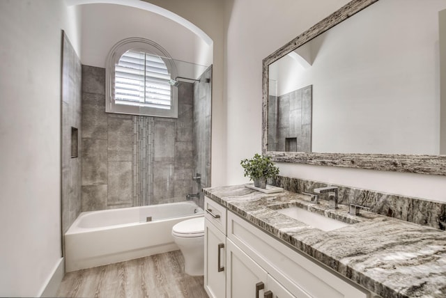 bathroom featuring toilet, washtub / shower combination, wood finished floors, and vanity