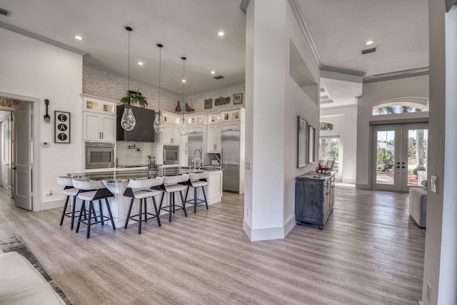 kitchen with glass insert cabinets, a large island with sink, and appliances with stainless steel finishes