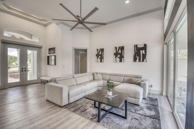 living room with a high ceiling, crown molding, wood-type flooring, and french doors