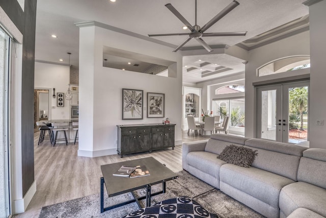 living room featuring baseboards, light wood-style flooring, a high ceiling, crown molding, and recessed lighting