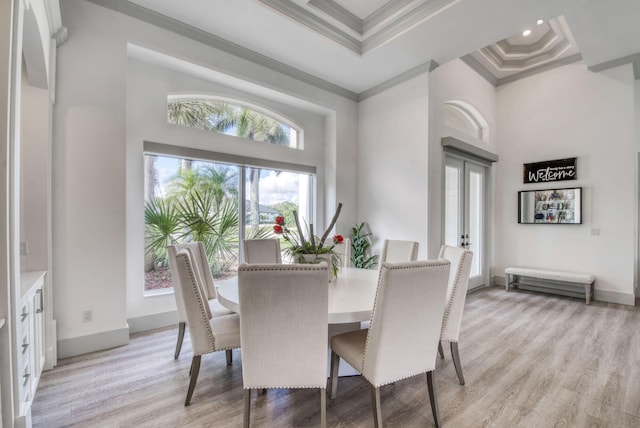 dining space with french doors, ornamental molding, a tray ceiling, a towering ceiling, and light hardwood / wood-style floors