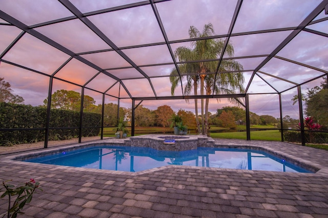 pool at dusk featuring a patio, a lanai, and a pool with connected hot tub