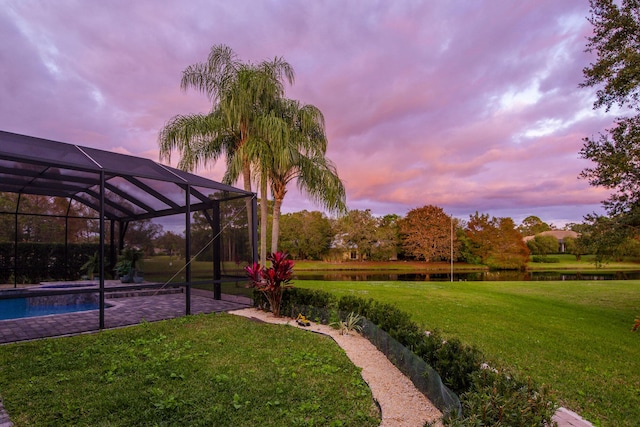 yard at dusk with a water view and a lanai