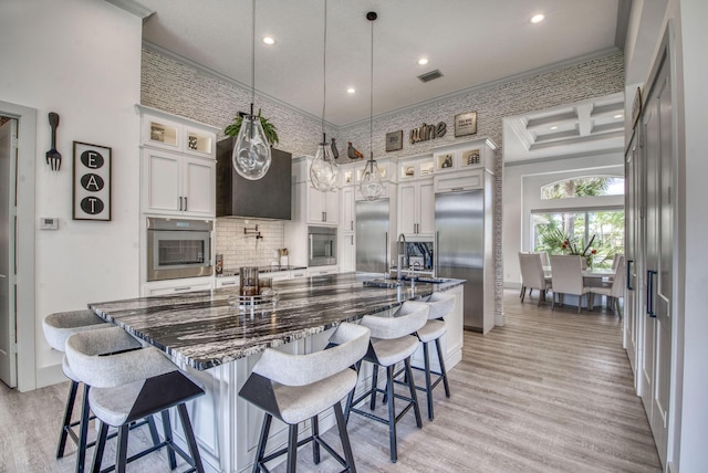 kitchen with pendant lighting, stainless steel appliances, glass insert cabinets, and white cabinets