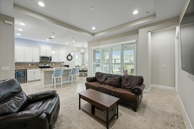 living room with light tile patterned floors, a tray ceiling, and wine cooler