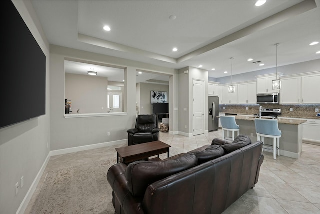 living room featuring a raised ceiling and light tile patterned flooring