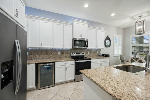 kitchen with backsplash, white cabinets, sink, stainless steel appliances, and beverage cooler