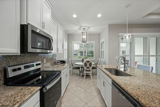 kitchen featuring light stone counters, stainless steel appliances, sink, pendant lighting, and white cabinets