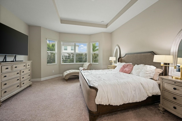 bedroom with a tray ceiling and dark colored carpet