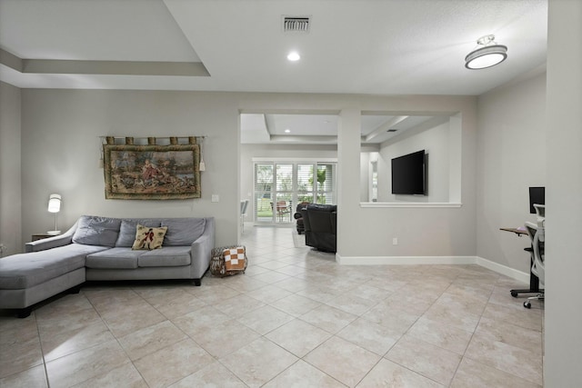 living room with light tile patterned floors and a raised ceiling