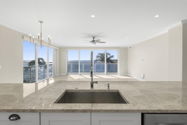 kitchen with ceiling fan with notable chandelier, white cabinetry, a wealth of natural light, and sink