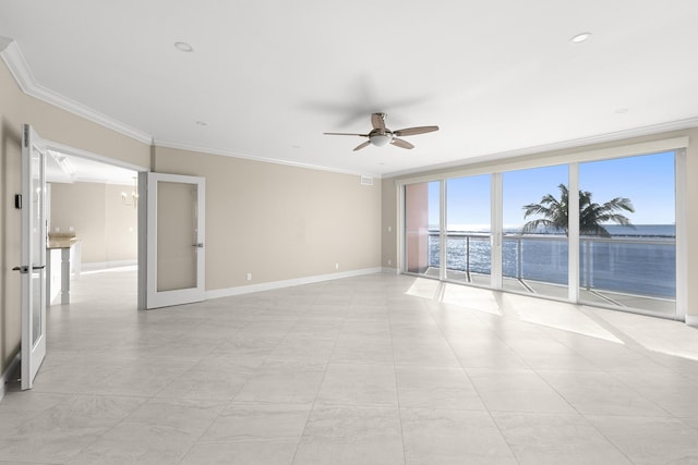 empty room featuring ceiling fan with notable chandelier, a water view, expansive windows, and crown molding