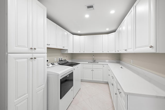 laundry area with washing machine and clothes dryer, sink, light tile patterned flooring, and cabinets