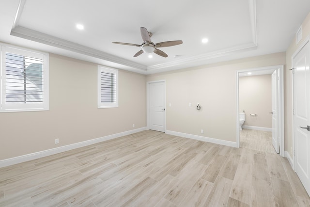 unfurnished bedroom featuring a tray ceiling, connected bathroom, ceiling fan, and light wood-type flooring