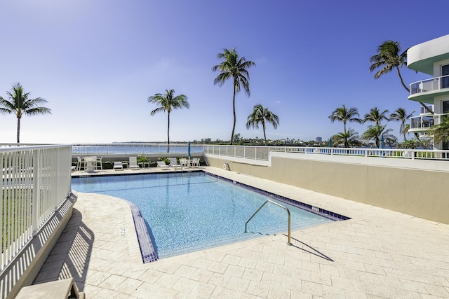 view of swimming pool featuring a water view and a patio