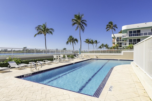 view of swimming pool with a patio area and a water view