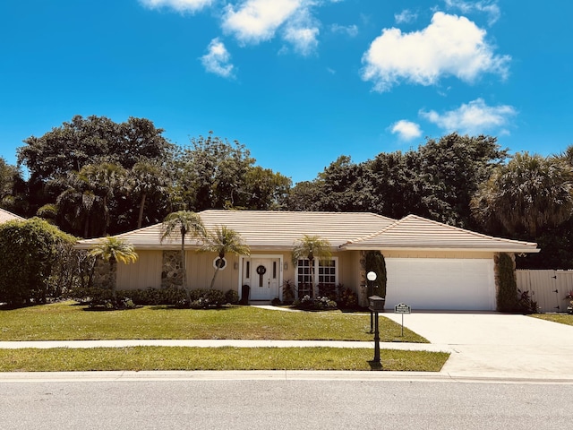 ranch-style house with an attached garage, concrete driveway, fence, and a front lawn