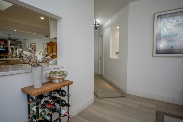 hallway featuring light wood-style flooring, baseboards, and recessed lighting