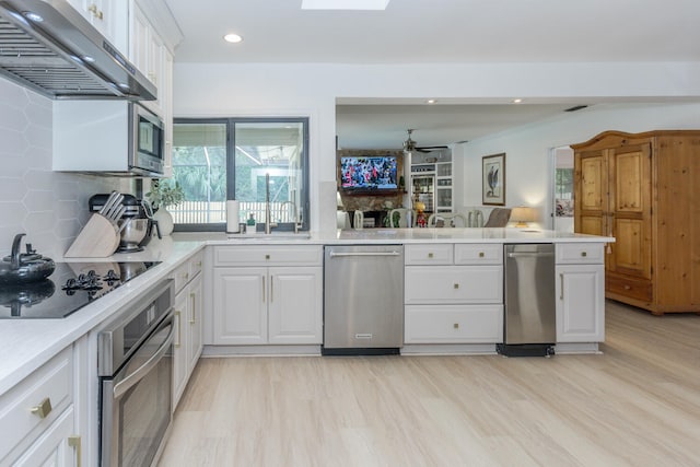 kitchen with recessed lighting, under cabinet range hood, white cabinetry, light countertops, and appliances with stainless steel finishes