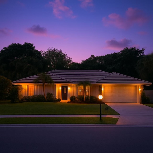 view of front of property featuring concrete driveway, an attached garage, a tiled roof, and a front yard