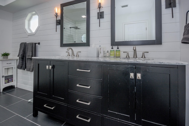 bathroom with double vanity, tiled shower, a sink, visible vents, and wooden walls