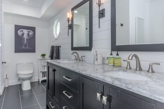 full bath featuring toilet, tile patterned flooring, double vanity, and a sink