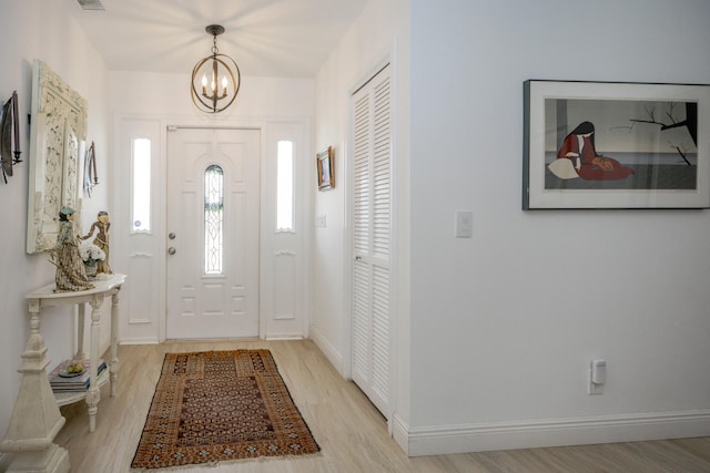 foyer entrance with a chandelier, light wood-style flooring, baseboards, and visible vents