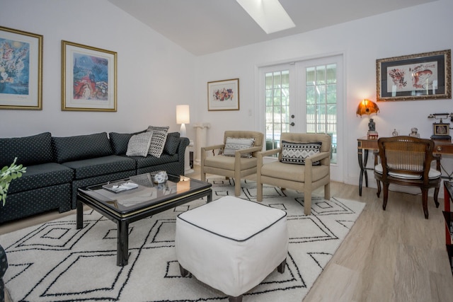 living area with light wood-style flooring, french doors, and vaulted ceiling with skylight
