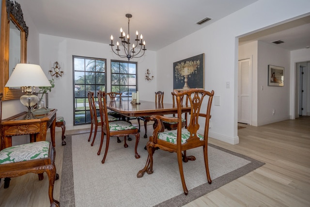 dining space featuring light wood-type flooring and an inviting chandelier