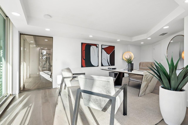 office featuring light hardwood / wood-style flooring and a tray ceiling