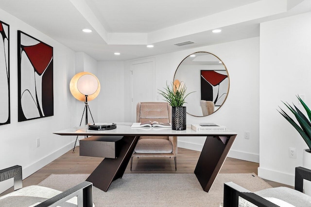 office with a tray ceiling and light hardwood / wood-style flooring