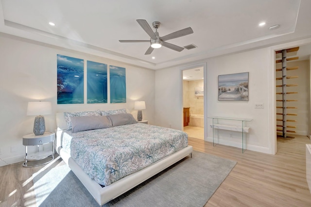 bedroom featuring a raised ceiling, visible vents, baseboards, and light wood finished floors