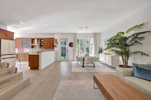 living room with sink, a chandelier, and light hardwood / wood-style flooring