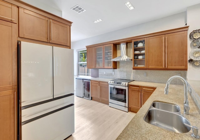 kitchen with a sink, visible vents, freestanding refrigerator, stainless steel electric range oven, and wall chimney exhaust hood