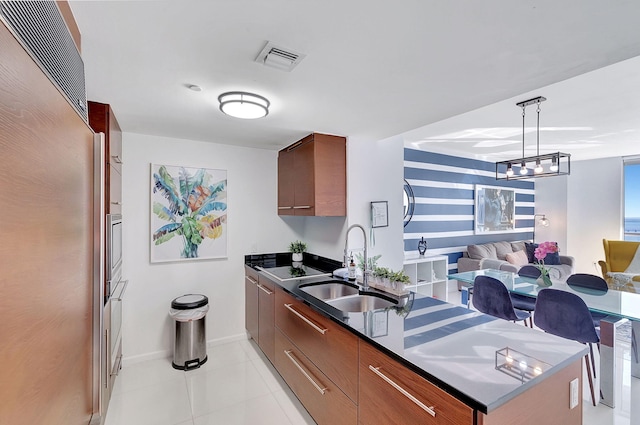 kitchen with decorative light fixtures, high end fridge, light tile patterned flooring, and sink