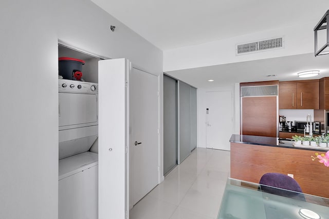 kitchen featuring sink, paneled refrigerator, light tile patterned floors, and stacked washer and dryer