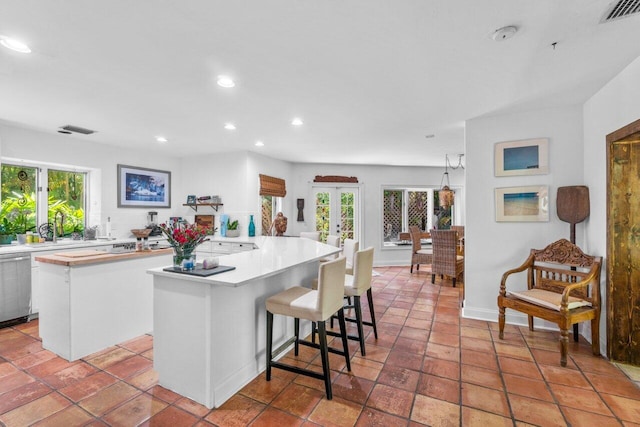 kitchen with a center island, french doors, white cabinets, tile patterned flooring, and a breakfast bar area