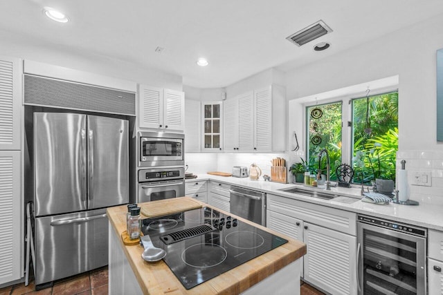 kitchen featuring decorative backsplash, sink, built in appliances, white cabinets, and wine cooler