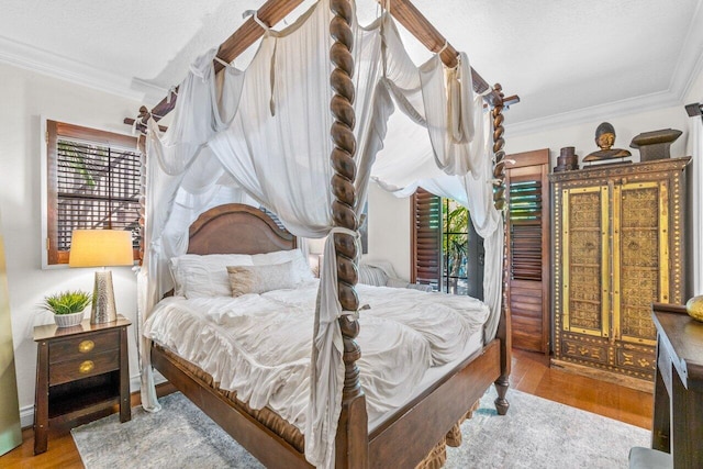 bedroom with wood-type flooring, a textured ceiling, multiple windows, and ornamental molding