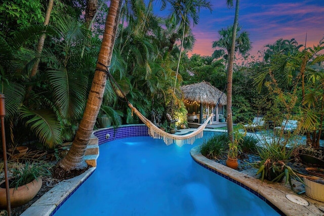 pool at dusk featuring a gazebo