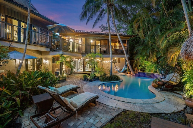 pool at dusk with a patio area and french doors