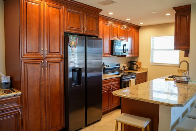 kitchen with light stone countertops, sink, stainless steel appliances, a kitchen breakfast bar, and light tile patterned flooring