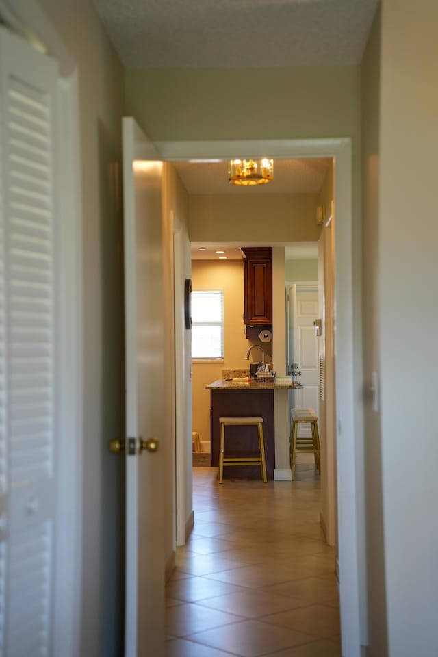 hallway featuring light tile patterned floors and a notable chandelier