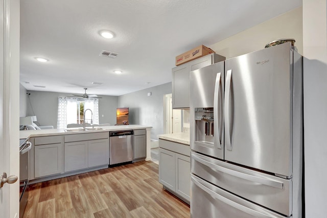 kitchen featuring ceiling fan, sink, light wood-type flooring, and stainless steel appliances